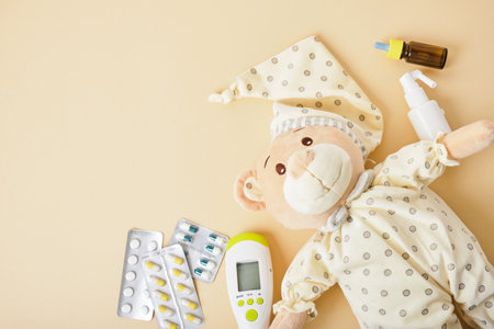 cute teddy bear, pills, nose drops, throat spray and non-contact infrared thermometer on beige background top viewの写真素材