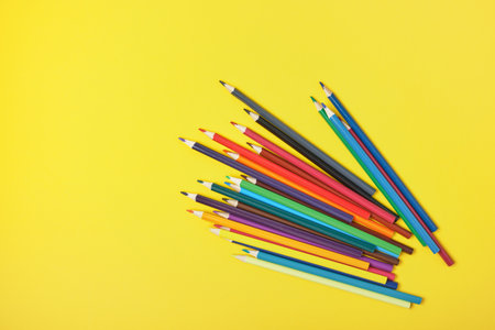 a bunch of colored pencils on a yellow backgroundの写真素材