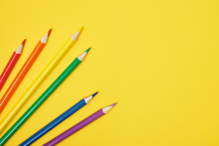 several colored pencils on a yellow background copy space top viewの写真素材