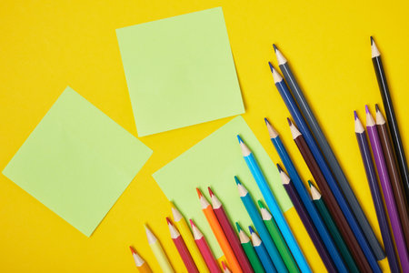 colored pencils and sticky notes on yellow background copy space top viewの写真素材