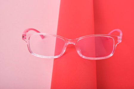 children's glasses on a pink and red background, glasses in a pink plastic frame copy spaceの写真素材