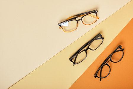 several pairs of glasses on beige and brown background, geometric background top view copy spaceの写真素材