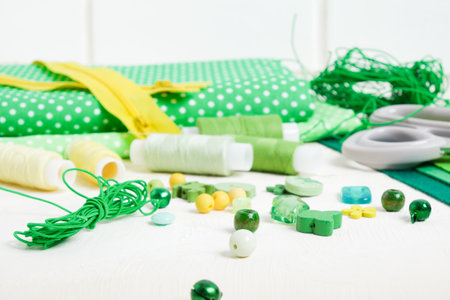 lace, spools of thread, scissors, fabrics, a zipper and accessories for sewing and needlework on the table, beads, buttons and pinsの写真素材