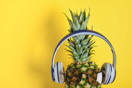 flyng ripe attractive pineapple in stylish sunglasses and headphones on yellow background copy spaceの写真素材