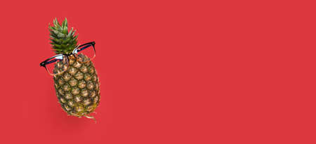levitating pineapple with glasses on a red background copy spaceの写真素材