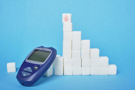 Blood Glucose meter device and ladder of sugar cubes on blue background