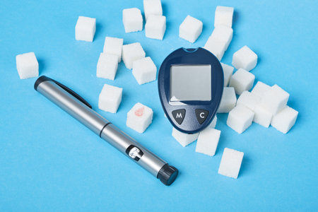 diabetes concept, sugar cube with drawn blood drop, sugar cubes, glucometer and syringe pen for...