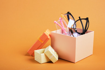 several different glasses in a beige gift box, small gift boxes on a brown background copy space, discounts and promotions in an optics storeの写真素材