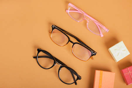 several different glasses and small gift boxes on a brown background copy space, discounts and promotions in the optics store top viewの写真素材