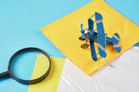 toy model of a vintage plane made of metal and several parcels and a magnifying glass on a blue...