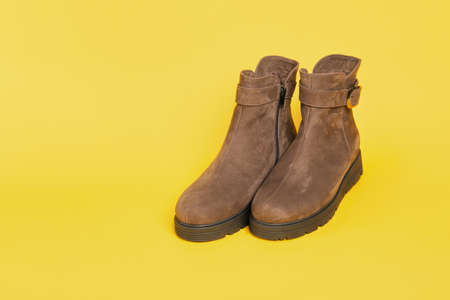 Womens brown suede fashion boots on a yellow background. copy spaceの写真素材