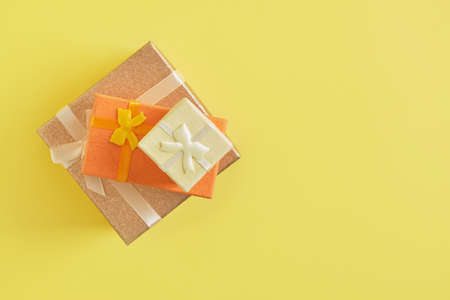 gift boxes of different colors, sizes and shapes on a yellow background copy space