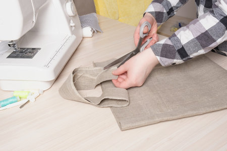 a woman cuts out the details of an eco bag, a shopper from natural linen with her own hands, a...