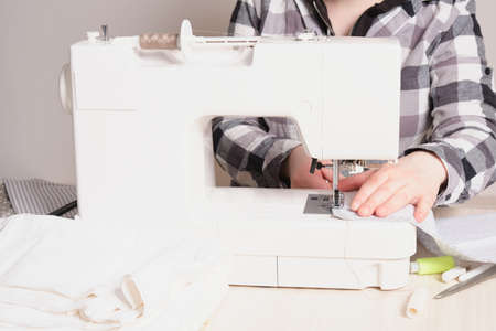 woman working with sewing machine, white sewing machine on the table, sewing materials tailoring...