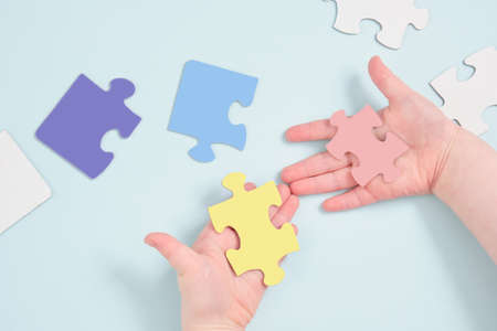 childrens hands colored hold puzzles on blue background, autism symbol, autism diagnosis conceptの写真素材