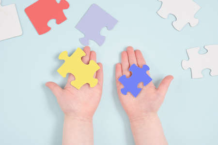 childrens hands colored hold puzzles on blue background, autism symbol, autism diagnosis conceptの写真素材