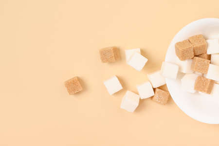 brown cane and white sugar cubes in white bowl on beige background copy spaceの写真素材