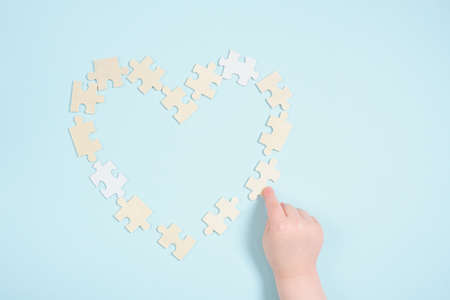 childrens hand and heart from wooden puzzles on a blue background