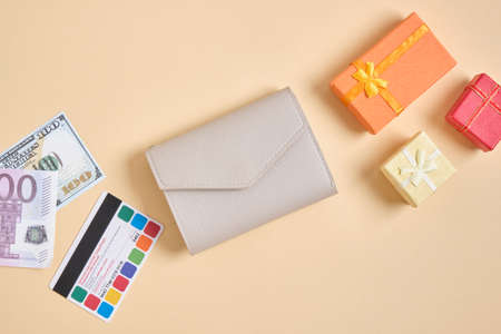 wallet, credit card, money and small boxes gifts on beige background