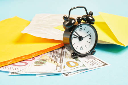 alarm clock, money and parcels on blue background, mail concept, tracking parcelsの写真素材