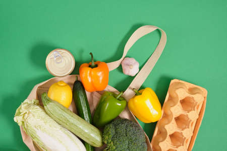 vegetables and other food items in fabric eco bag on green background top view zero waste lifestyle...