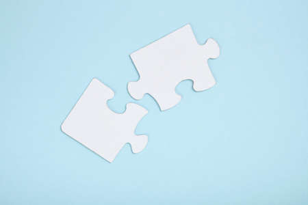 White jigsaw pieces on blue paper background close up copy space top view mock up