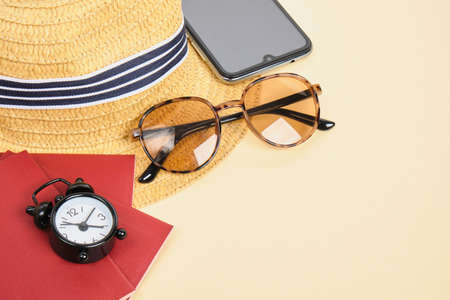 straw hat, sunglasses, alarm clock and passport on beige background, time for travel and beach...