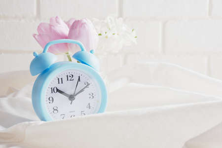 blue alarm clock, flowers on the bed, spring morning mood concept, beautiful tulips and hyacinth in the spring morning copy spaceの写真素材