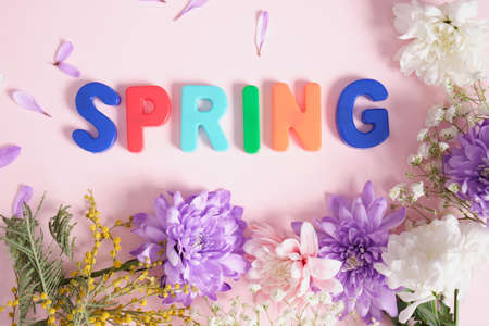 inscription spring in flowers on a pink background top view spring mood conceptの写真素材