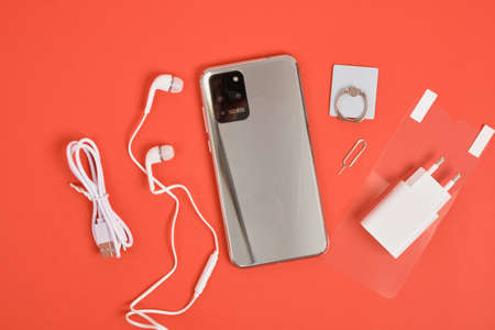 modern smartphone with 3 cameras with metal body and smartphone components on a red background top view copy spaceの写真素材