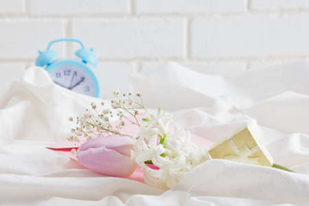 blue alarm clock, flowers on the bed, spring morning mood concept, beautiful tulips and hyacinth in the spring morningの写真素材