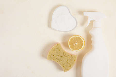 spray bottle, sponge, lemon and soda on beige backgrund top vire copy space