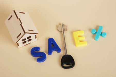 model of a small wooden house key and inscription sale, sale and purchase of real estate, construction or rent of a private house beige backgroundの写真素材