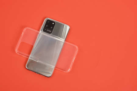 modern smartphone with 3 cameras with metal body and transparent silicone case on a red background...