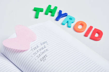 notepad, felt thyroid gland and the inscription from plastic letters thyroid gland on a gray background, treatment of thyroid diseases with the help of diet conceptの写真素材