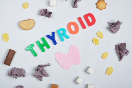 wads of paper, sweets, felt thyroid gland and the inscription thyroid gland on a gray background ,, treatment of thyroid diseases with the help of diet concept, junk foodの写真素材