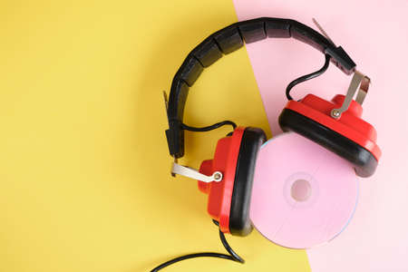 old red headphones and pink cd disk on yellow background copy space top viewの写真素材