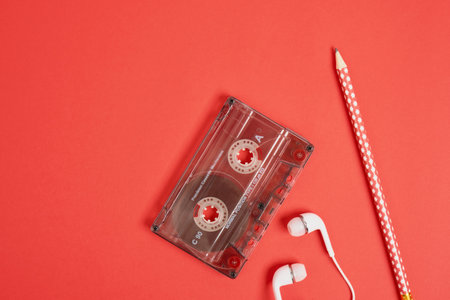 smartphone pencil headphones and audio cassette on red background, memories concept top view copy...