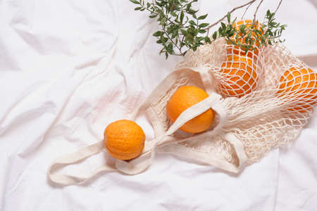 mesh eco bag with oranges on white cloth backgroundの写真素材