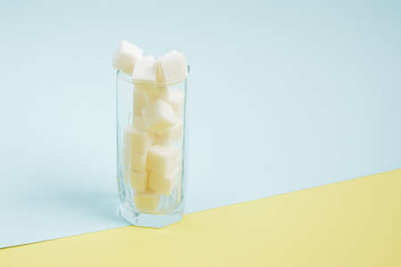 sugar cubes in a glass on a blue and yellow background copy space Too much sugar in drinks conceptの写真素材