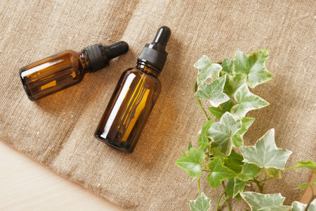 Brown glass bottle dropper with cosmetic oil and plant on linen fabric, brown backgroundの写真素材