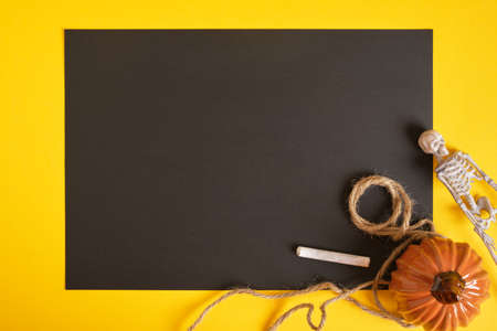 halloween mockup, blank black sheet of paper and halloween decor on a yellow background, copy space top viewの写真素材
