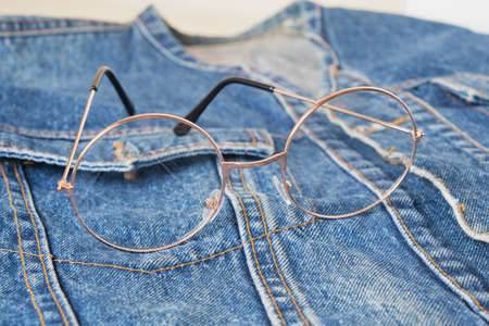 eyes glasses with round metal frames on the pocket of a blue denim jacket, trend eyes glasses, retro style copy spaceの写真素材
