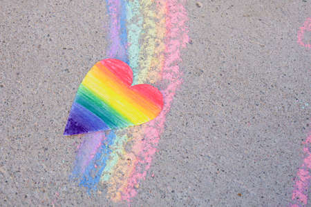 paper heart painted in rainbow colors of lgbt community and rainbow painted in chalk on asphalt, pride month conceptの写真素材