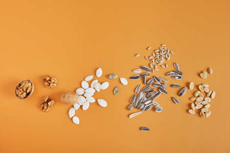a handful of different nuts and seeds on a brown background, peanuts, sunflower seeds, pumpkin and walnutの写真素材