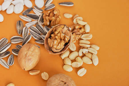 a handful of different nuts and seeds on a brown background, peanuts, sunflower seeds, pumpkin and...