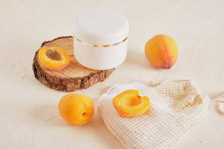 apricots plastic white jar for cream or cosmetics on a wooden podium from a saw cut from a tree on a light background against a white brick wallの写真素材