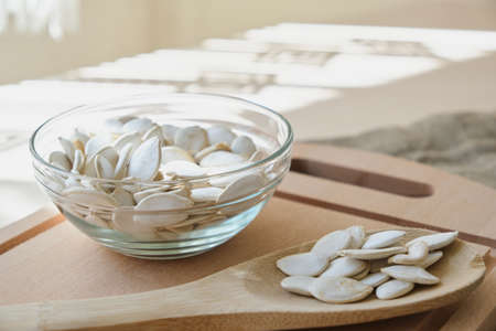 Pumpkin seeds in white bowl and spoon on the flax on the table copy spaceの写真素材