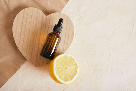 lemon and brown glass bottle with dropper for serum or cosmetic oil on a wooden podium in the shape of a heart, eco friendly body care conceptの写真素材