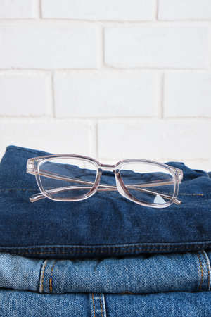 stylish eye glasses on a stack of jeansの写真素材